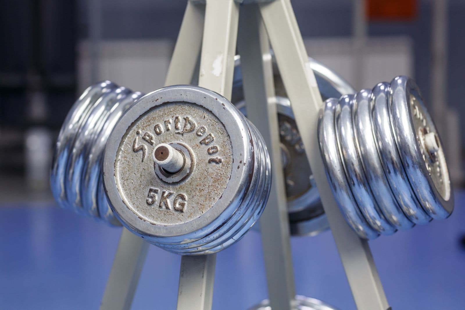 Chrome dumbbells stacked on a weight rack near the nutrition bar