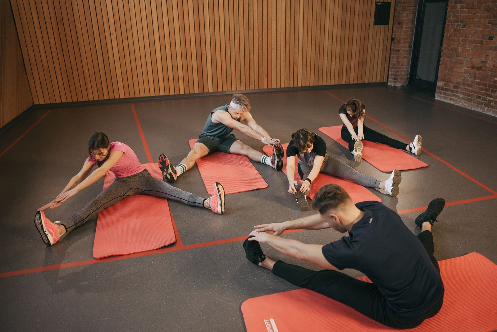 Group fitness class stretching together on red mats in the IronForge studio