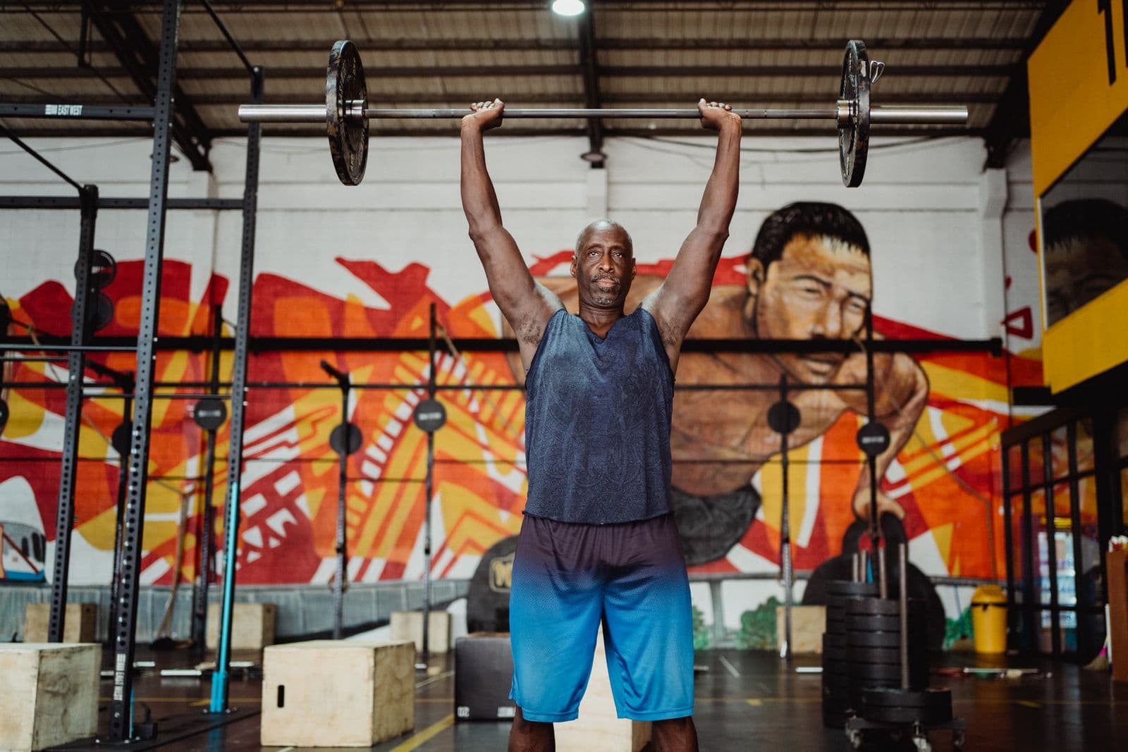 Focused weightlifter performing a barbell press in a dramatically lit training space