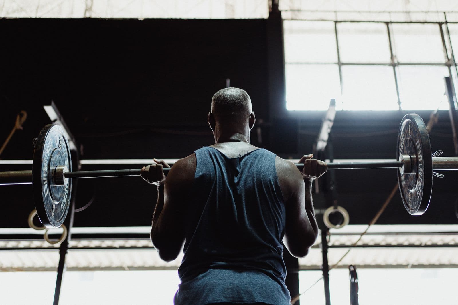 Athlete lifting a loaded barbell overhead during a strength training session