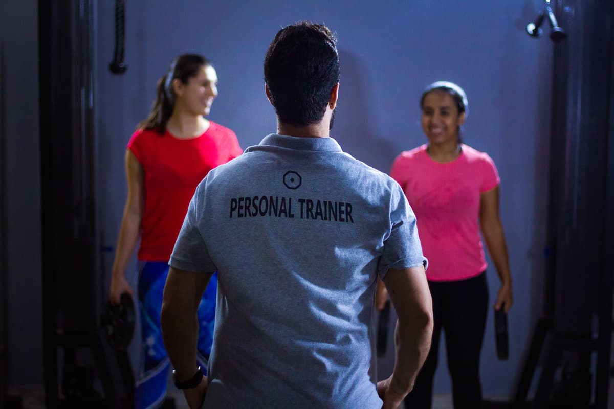 Coach guiding two smiling clients through a workout